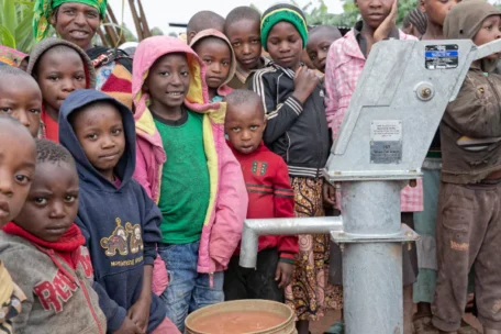 a group of people standing in front of a water pump
