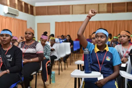 a classroom of students with one raising up their hand