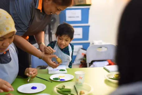 Rythm 18 a teacher and a child with plates of paint