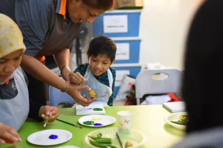 a teacher and a child with plates of paint
