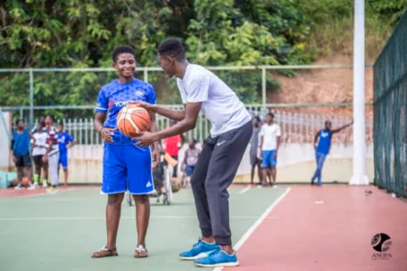 Rythm 8 man holding a basketball next to a boy in a volleyball court