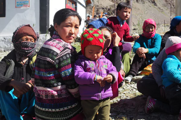 woman staring at the camera with her child wearing a purple jacket and a red cap