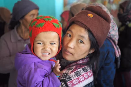 Rythm 7 woman holding up her child with a red wool cap