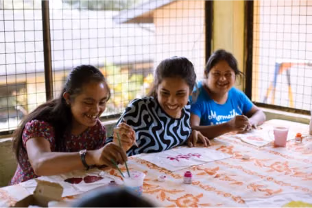 Rythm 6 three girls laughing while doing arts and craft