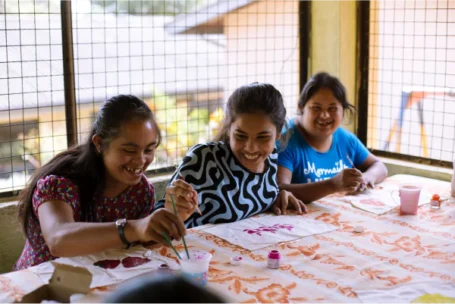 three girls laughing while doing arts and craft