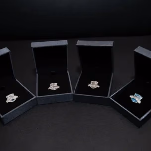 metallic achievers club pins in open up boxes black background
